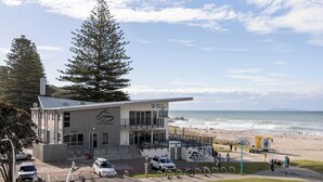 Un bâtiment moderne, sur lequel on peut lire l’inscription « Port de Tauranga », qui offre une vue sur la plage et l’océan.