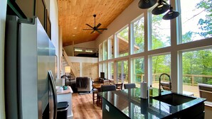 A spacious kitchen with a large island, wooden ceiling, and large windows offering a view of the outdoors. - Cedar Hill Cabin 2 bed 2 bath cabin in the Ozarks • Hot Tub • (Harrison)