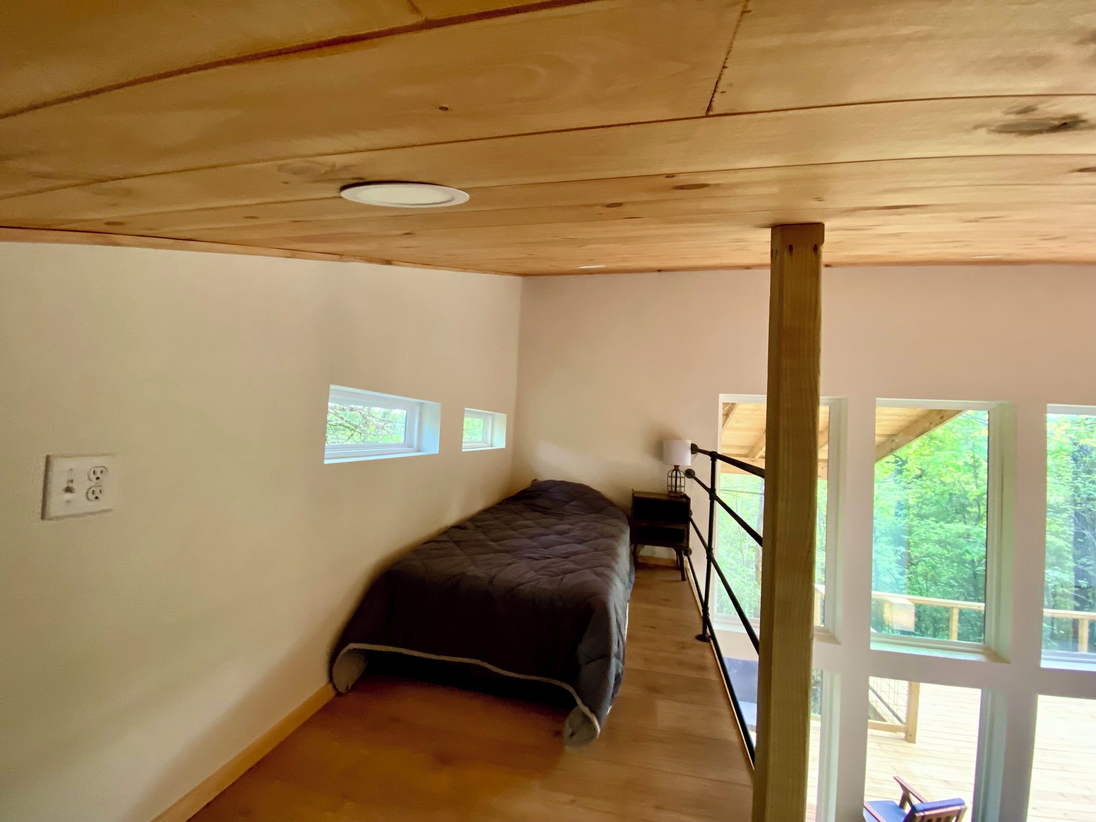 A bedroom with a bed, a small table, and a window.