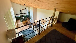A spacious living area with a high ceiling, a staircase leading to an upper floor, and a view of a kitchen and dining area. - Cedar Hill Cabin 2 bed 2 bath cabin in the Ozarks • Hot Tub • (Harrison)