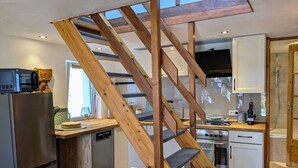 A modern kitchen with a wooden staircase, stainless steel appliances, and a view of the outdoors.