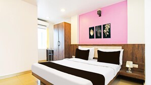 Una camera d'albergo moderna con un letto grande, un armadio, un comodino con una lampada e una parete con tre quadri incorniciati.