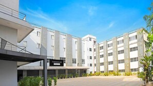 Un edificio moderno con un cartello che riporta la scritta 'TOWNHOUSE' e il logo del servizio aziendale. Si tratta di una struttura a più piani con tetto piatto e un'area d'ingresso coperta.