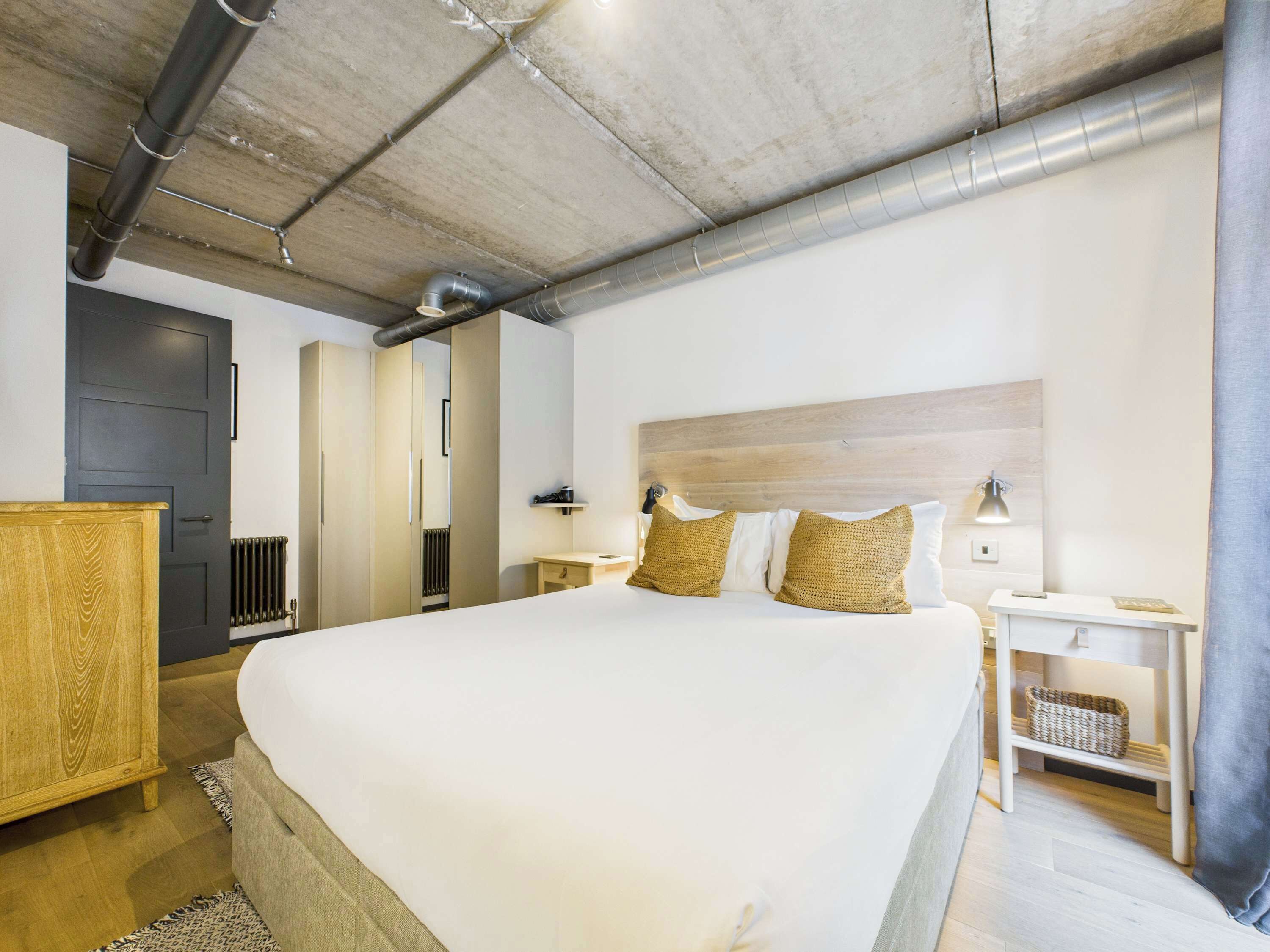 Una camera da letto moderna con un letto grande, una testiera in legno, comodini e un armadio.