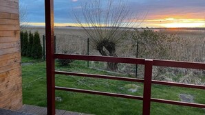 Une cabane en bois offrant une vue sur un coucher de soleil se déclinant sur un champ.