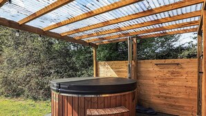 A hot tub under a wooden pergola with a metal roof, surrounded by a wooden deck and a wooden fence. - 6 Person Holiday Home in Gedser (Gedser)