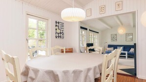 A dining area with a round table, white chairs, and a hanging light fixture. - 6 Person Holiday Home in Gedser (Gedser)