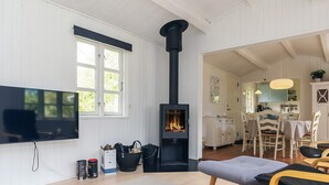 A cozy living room with a fireplace, a television, and a dining area with chairs and a table. - 6 Person Holiday Home in Gedser (Gedser)