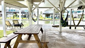 Un espacio al aire libre cubierto con mesas de picnic y hamacas.