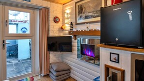 A cozy room with a fireplace, a television, and a refrigerator. - Chalet in Tintagel With Stunning Sea Views (Tintagel)