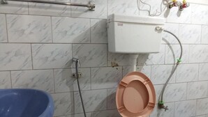 A bathroom with a toilet, a blue basin, and a shower. - Backpackers Hostel  (Darjeeling)