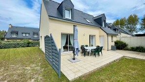 A two-story house with a tiled patio, a dining table with chairs, and a covered outdoor seating area. - L'Irisée-6p-Quiberon-500m Thalasso and beach parking lot (Quiberon)