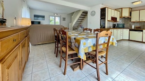 A spacious kitchen with wooden cabinets, a dining table with chairs, and a staircase leading to another level. - L'Irisée-6p-Quiberon-500m Thalasso and beach parking lot (Quiberon)