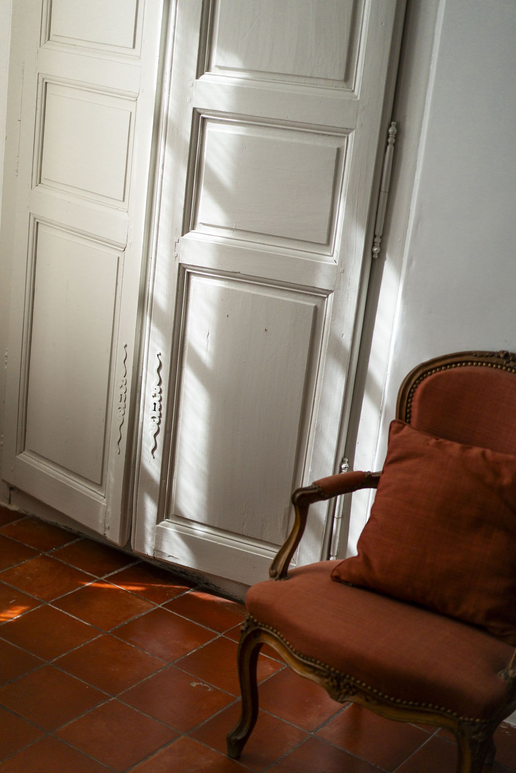 Um quarto com uma porta branca e uma cadeira marrom.