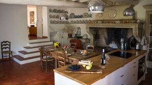 Eine Küche mit Holzeile, Kamin und Essbereich mit Stühlen und Tisch.