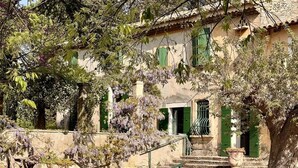 Ein traditionelles Gebäude mit einer Steintreppe, die zu einer Tür mit grünen Fensterläden führt.