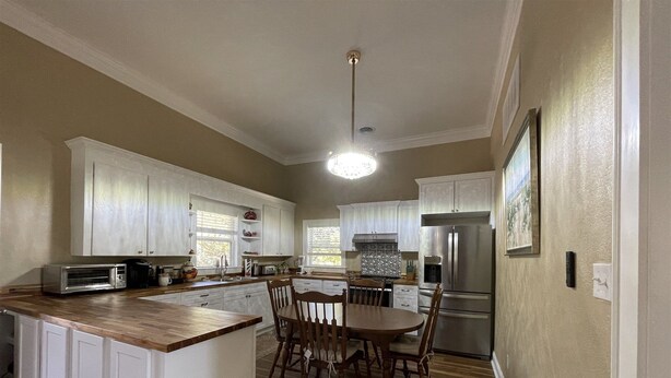 A kitchen with white cabinets, a wooden dining table, and a built-in island. - Gracie's Place 2 Bedroom Cottage (Avon)