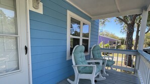A porch with two rocking chairs, a blue exterior, and a white door. - Gracie's Place 2 Bedroom Cottage (Avon)