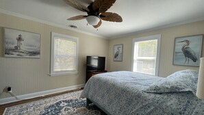 A bedroom with a bed, a ceiling fan, a television, and artwork on the walls. - Gracie's Place 2 Bedroom Cottage (Avon)