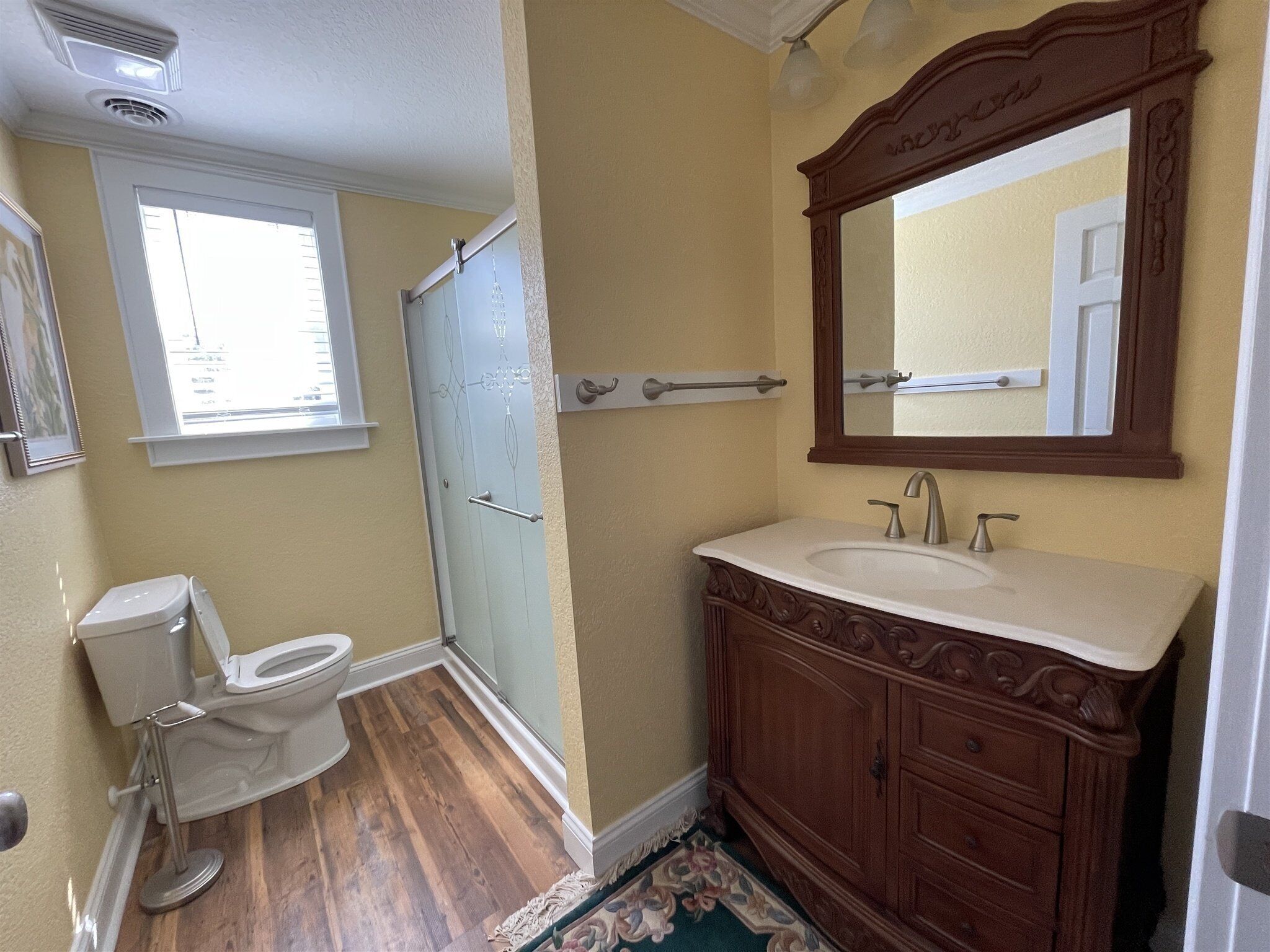 Une salle de bain comprenant des toilettes, un lavabo, un meuble-lavabo et une douche.