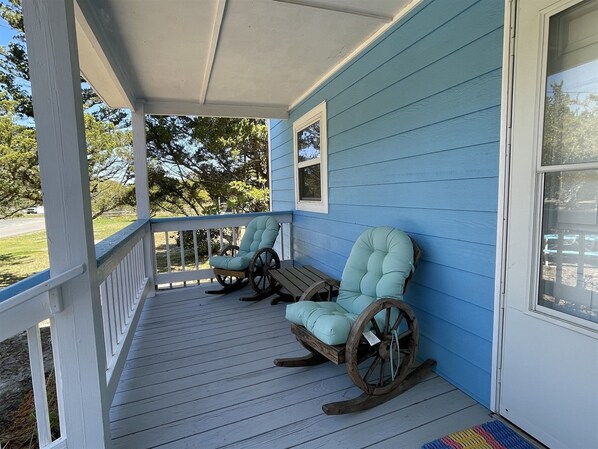 A porch with two rocking chairs and a wooden table. - Gracie's Place 2 Bedroom Cottage (Avon)