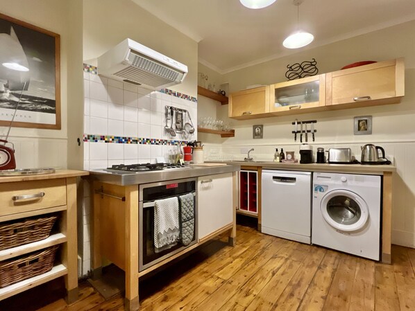 A compact kitchen with a gas stove, oven, dishwasher, and washing machine.