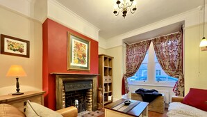 A cozy living room with a fireplace, leather sofas, a coffee table, and a bookshelf.