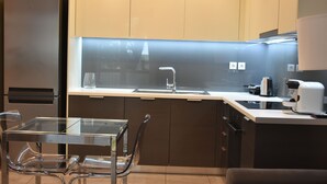 Eine moderne Küche mit einem Edelstahlkühlschrank, einem Glastisch und einer Kaffeemaschine.