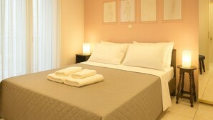 Ein ordentlich bezogenes Bett mit weißen Leinentüchern und Handtüchern, eine Nachttischlampe und drei gerahmte Skizzen an der Wand.