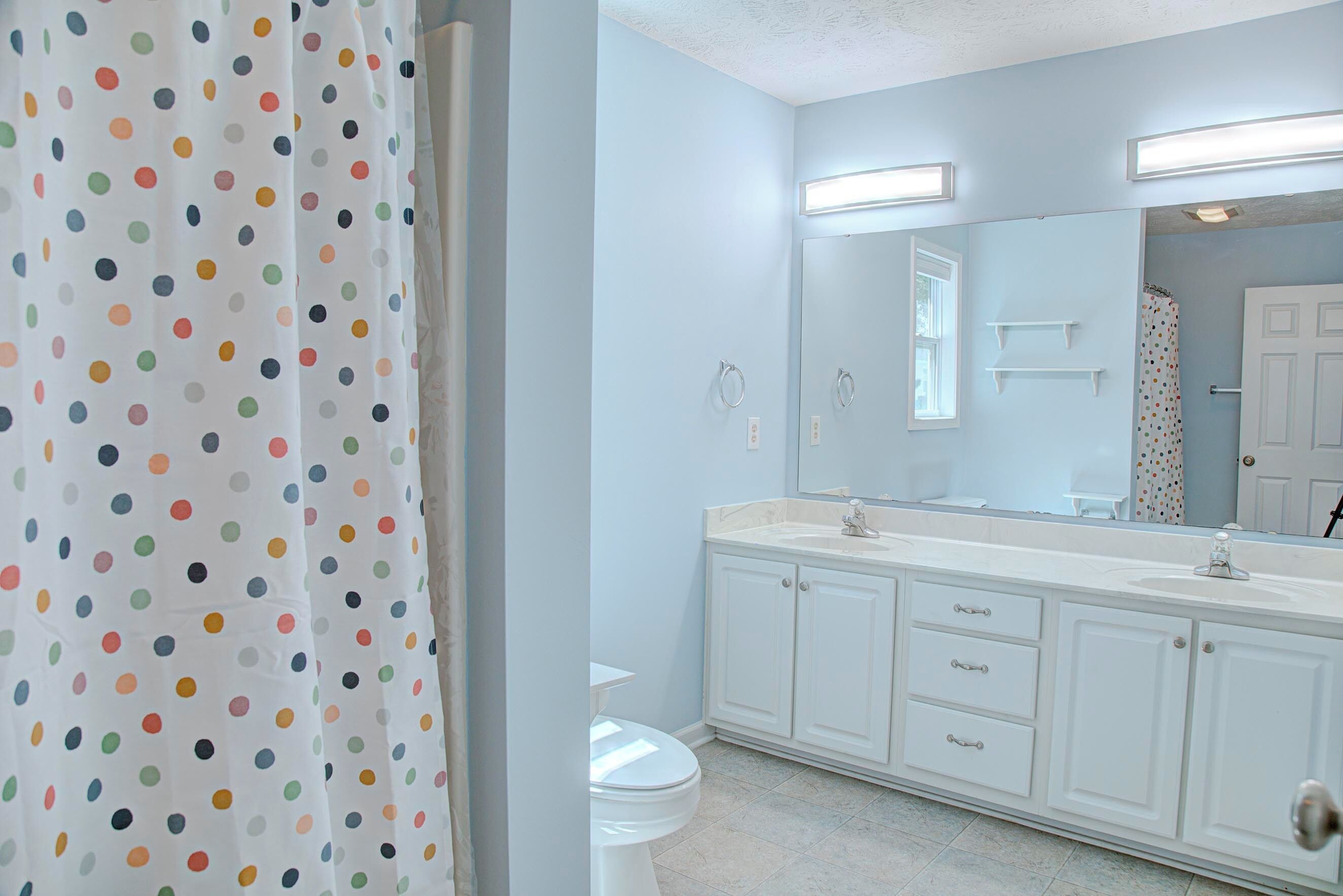 A bathroom with a white toilet, a white sink, and a mirror above the sink. There are two cabinets below the mirror.
