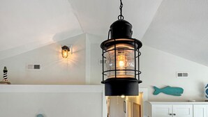 A kitchen with white cabinets, a hanging black lantern light, a seahorse wall decoration, and a fish-shaped wall art piece. - Relaxing family and dog friendly getaway located in Hatteras (Hatteras)