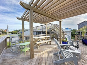 Une terrasse en bois avec des tables et des chaises pour pique-niquer, une pergola et un escalier menant à un niveau supérieur.