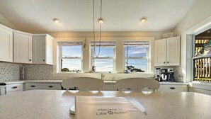 A modern kitchen with white cabinets, a large island, and a view of the ocean. - Relaxing family and dog friendly getaway located in Hatteras (Hatteras)
