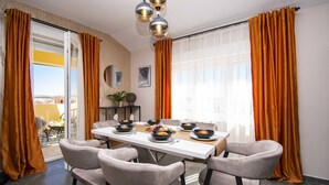 A dining area with a table set for four, chairs, a ceiling light fixture, and a view through a glass door. - 2-bedroom Coastal Apartment in Vodice (Vodice)