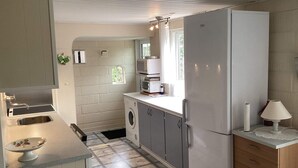 Eine kleine Küche mit Waschmaschine, Kühlschrank und Spüle.