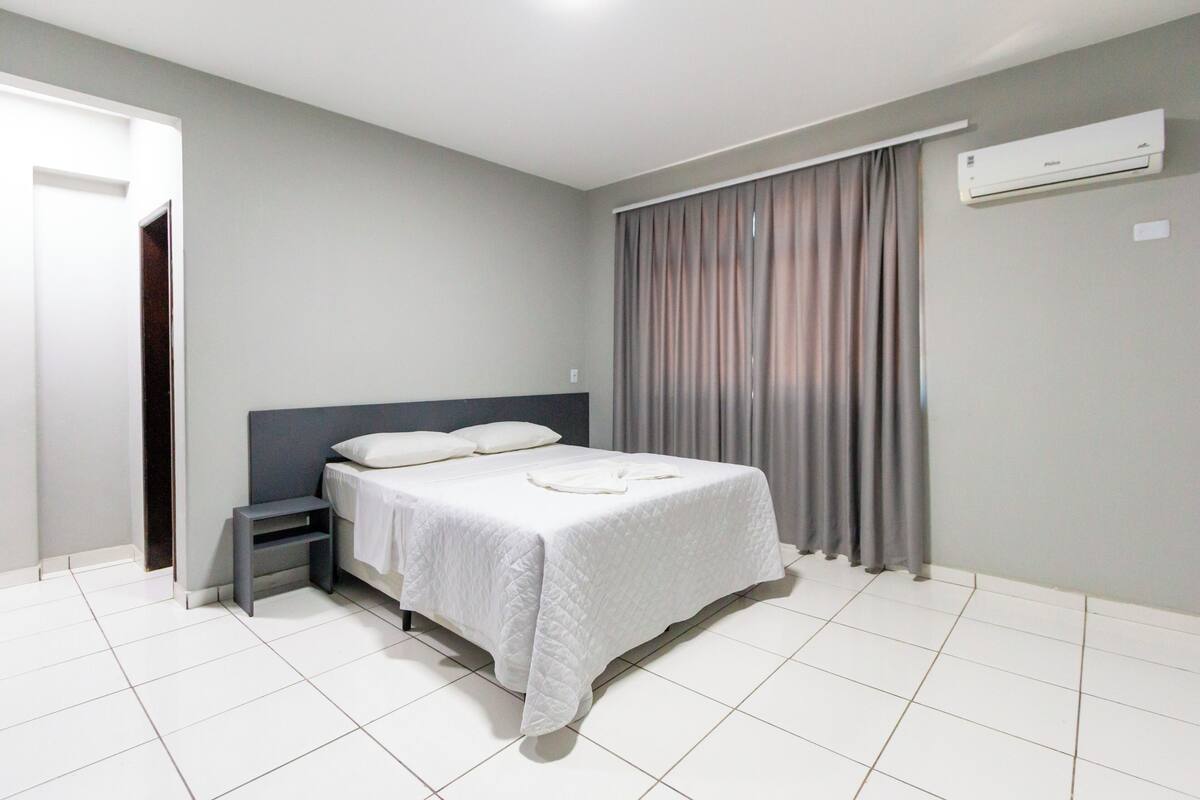 A bedroom with a bed, bedside table, and curtains.