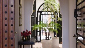 Un couloir avec une porte en bois, une plante en pot et une table sur laquelle se trouve un vase.