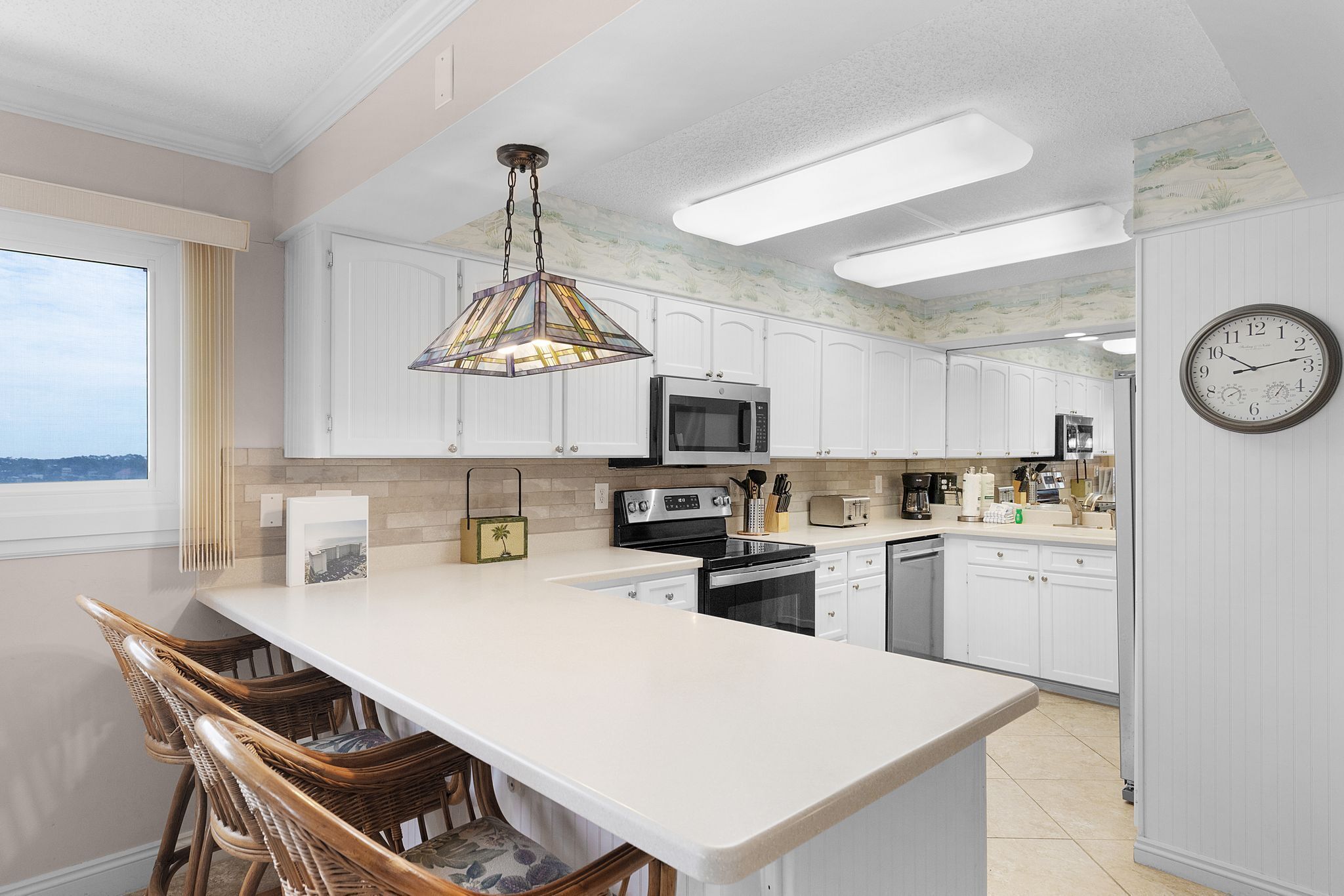 A modern kitchen with white cabinets, a large island, and a hanging light fixture.