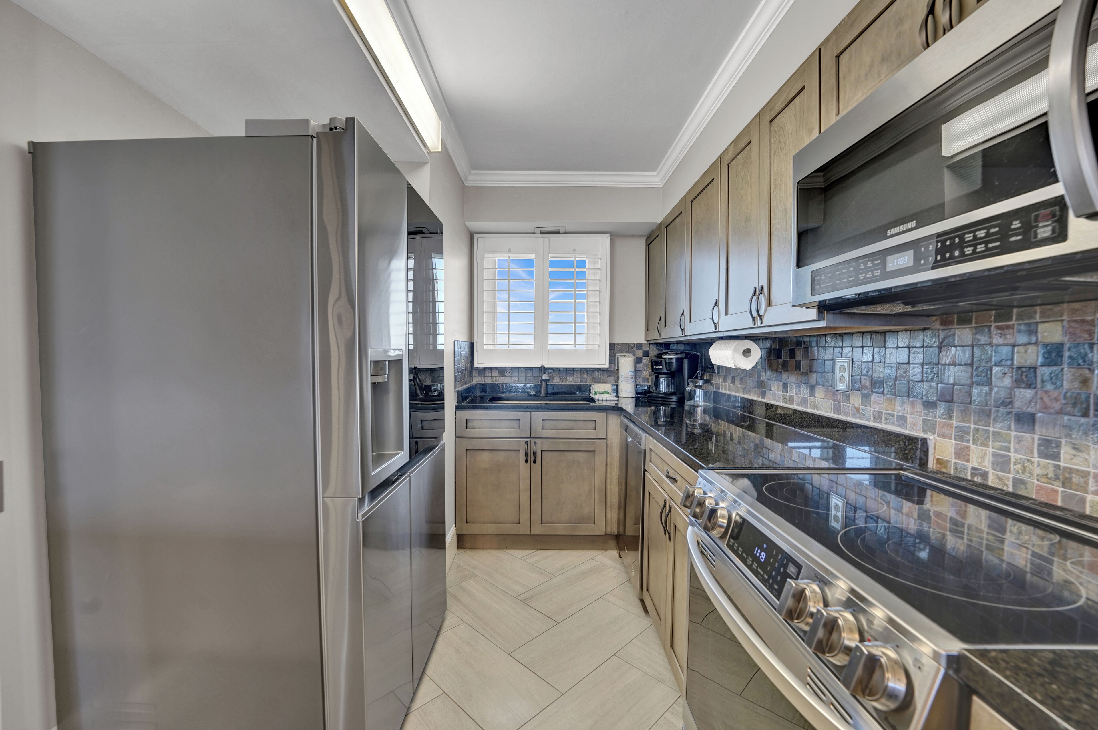 A modern kitchen with stainless steel appliances, wooden cabinets, and a tiled backsplash.