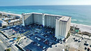 A large hotel with a parking lot and a view of the ocean.