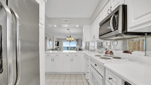 Una cocina moderna con armarios blancos, electrodomésticos de acero inoxidable y una isla grande con un hervidor.