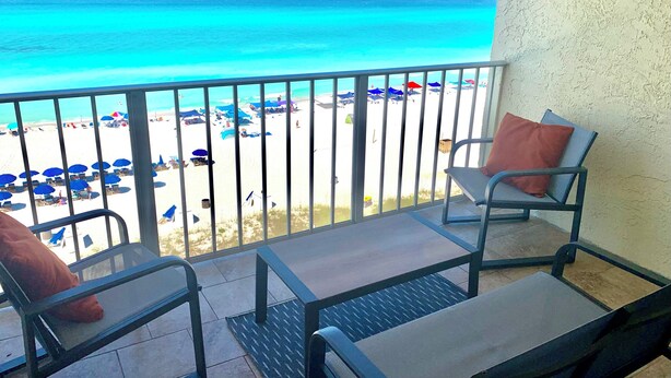 Ein Balkon mit Blick auf einen Strand, mit einem Stuhl und einem Tisch.
