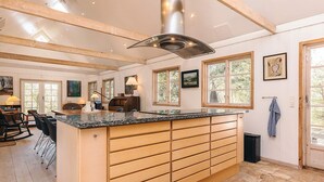 A spacious kitchen with a large island, wooden beams, and large windows. - 4 Star Holiday Home in Liseleje (Liseleje)