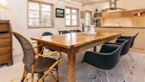 A spacious kitchen with a wooden table, black chairs, and a modern stove. - 4 Star Holiday Home in Liseleje (Liseleje)