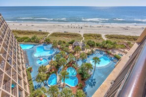 Un hôtel doté de plusieurs piscines, entouré de palmiers et offrant une vue sur la plage.