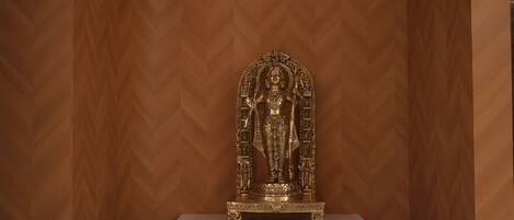 A statue on a pedestal against a wooden wall.