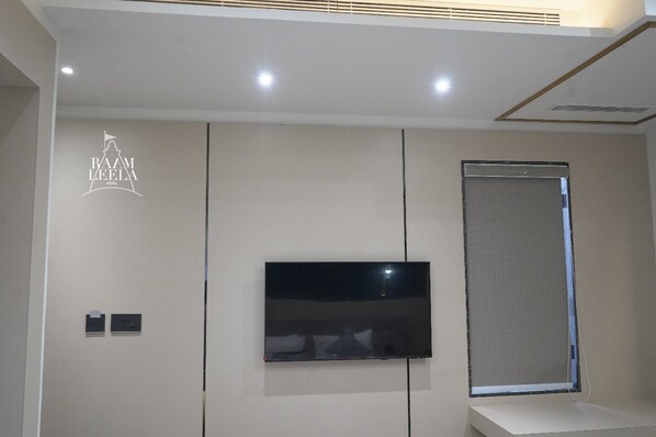 Een moderne hotelkamer met een flatscreen televisie aan de muur, een groot raam met uitzicht en een plafond met inbouwverlichting.