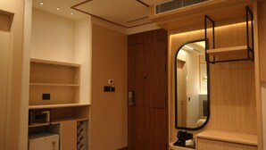 A modern hotel room with a wooden wardrobe, a built-in microwave, and a large mirror. - Raam Leela Hotel (Faizabad)