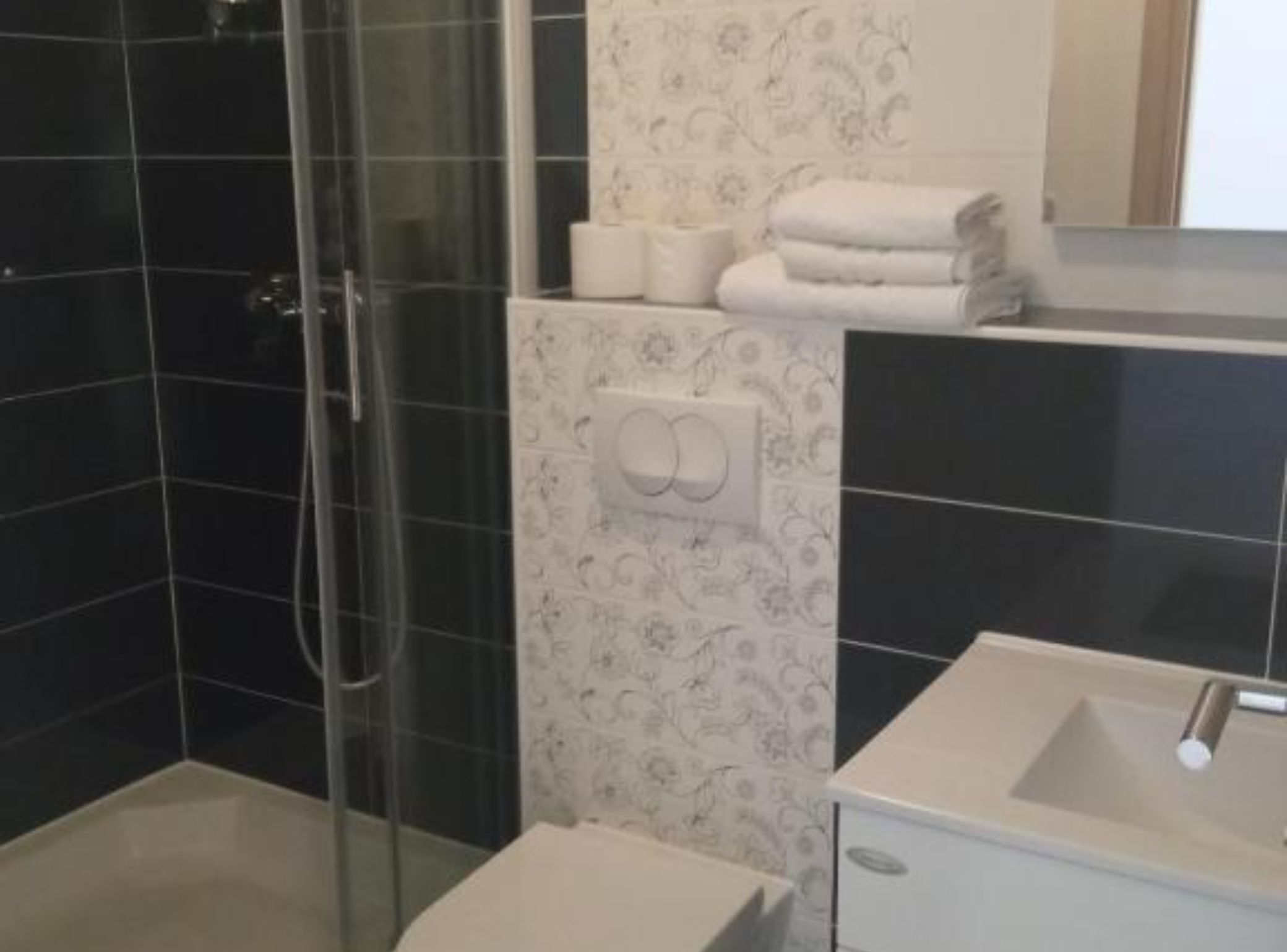 A modern bathroom with a glass-enclosed shower, a white sink, and a toilet.