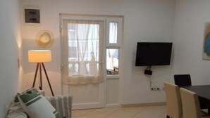 Ein Zimmer mit einem Bett, einem Schreibtisch, einem Stuhl, einem Fernseher und einem Fenster mit Vorhängen.